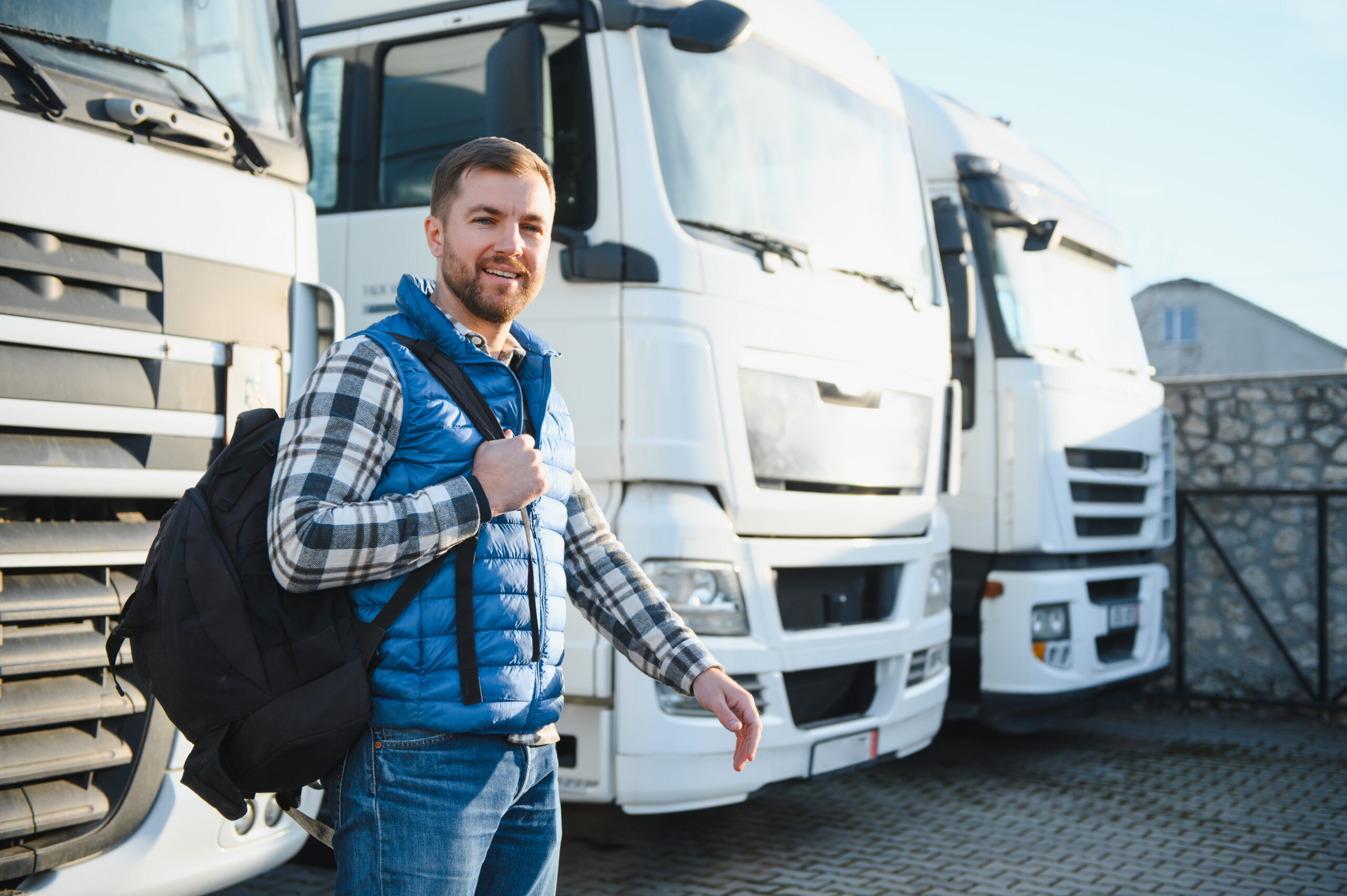 Motorista de empresa de transporte ao lado de caminhões — compra de pneus em grande volume